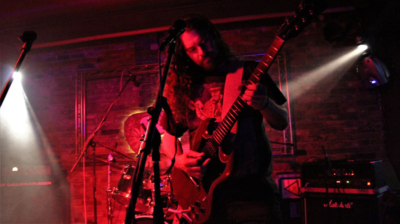 A man with long hair and glasses playing guitar.