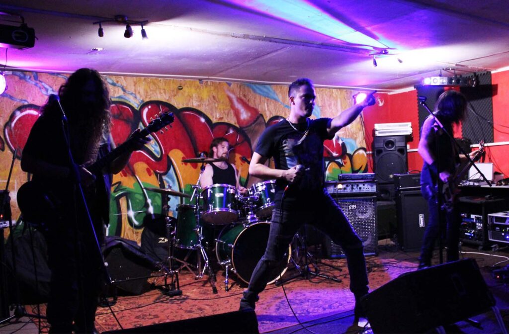 A band performing in front of a wall with graffiti.