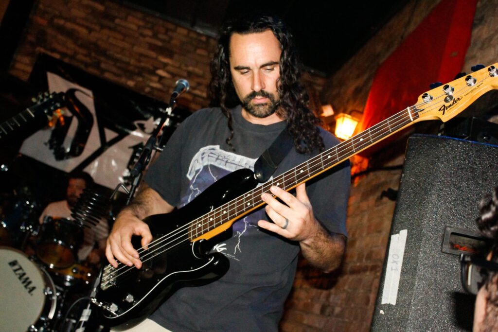 A man playing the bass guitar in front of some lights