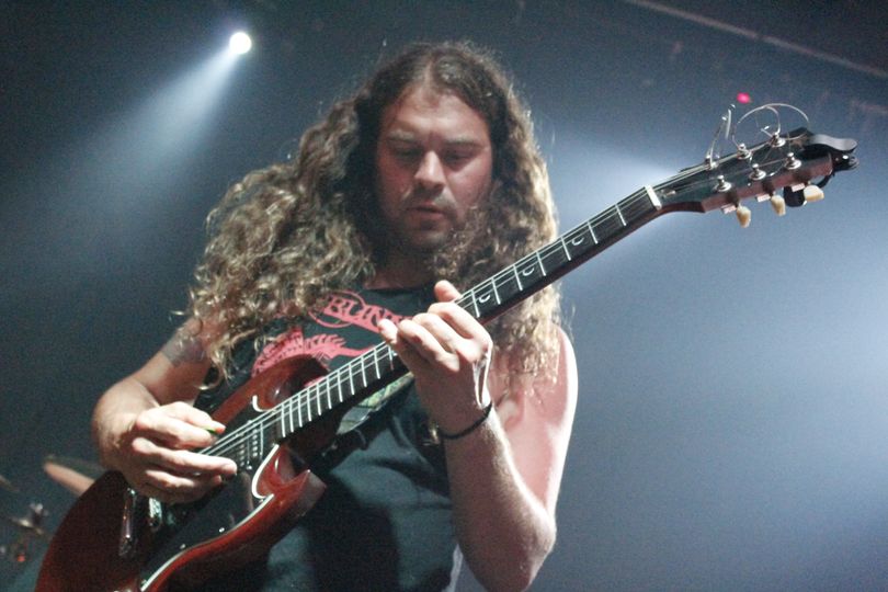 A man with long hair playing an electric guitar.