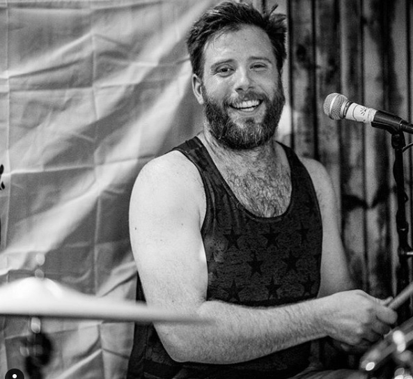 A man with beard and mustache playing drums